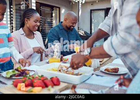 Eine glückliche Familie, die gemeinsam im Garten zu Mittag essen kann. Stockfoto