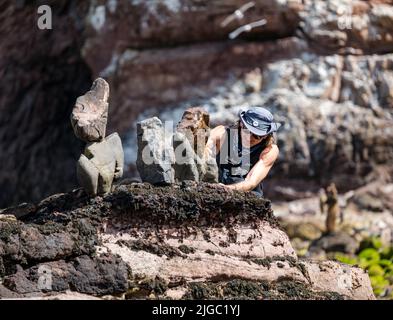 Dunbar, East Lothian, Schottland, Großbritannien, 9.. Juli 2022. European Stone Stacking Championship: Die Teilnehmer haben 3,5 Stunden Zeit, ein künstlerisches Kunstwerk aus den Felsen am Eye Cave Beach zu kreieren. Im Bild: Pedro Duran, Steinstapler Stockfoto