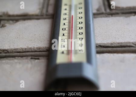 Unschärfenthermometer. Wärme, Thermometer zeigt die Temperatur in der grauen Wand, Sommer heiß ist. Heißer Sommer oder Hitzewelle Hintergrund, glühende Sonne mit der Stockfoto