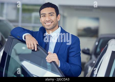 Ich finde das perfekte Auto für Sie. Beschnittenes Porträt eines hübschen jungen männlichen Autoverkäufers, der im Ausstellungsraum arbeitet. Stockfoto