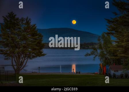 Der Vollmond erhebt sich über dem Mt. Kersarge, Pleasant Lake, New London, NH. Ort, an dem Kate Smith das Lied „When the moon Coming over the Mountain“ schrieb. Stockfoto