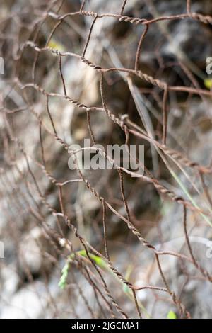 Ein schützendes Metallgeflecht schützt die Felsen vor Steinschlag. Metallisches Netz schützt die Straße vor Erdrutschen und fallenden Steinen. Sichere Bergausrüstung Stockfoto