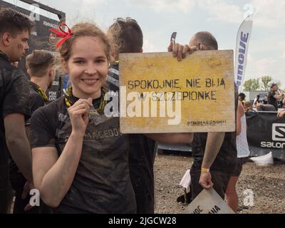 Warschau, Polen - 25. Mai 2019: Porträt eines glücklichen jungen Mädchens in schmutziger Kleidung mit einem gelben Holzbrett mit der Aufschrift "Entspannen, nicht schlagen die Stockfoto