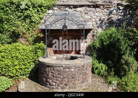 Ein Gedenkbrunnen aus Naturstein und verzierten Eisenarbeiten auf dem Gelände der Dunster Priory Church, Somerset, England Stockfoto