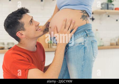 Glücklicher Mann, der den Bauch seiner Schwangeren berührt, glückliche Familie. Hochwertige Fotos Stockfoto