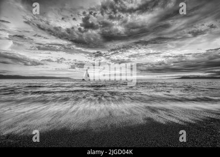 Detaillierte Wolken sind über, wie Ein kleines Boot bewegt sich entlang der Ocean Horizon Black and White Stockfoto