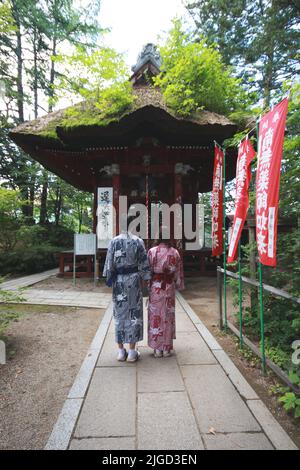 Ein Paar, das vor einem japanischen Schrein steht, während es Yukatas in Kusatsu, Japan, trägt. Stockfoto