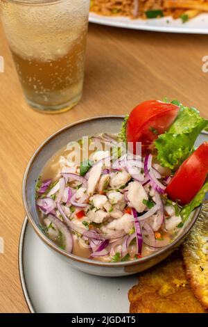 Ceviche aus der Nähe mit Getränk und Tomatensalat Stockfoto