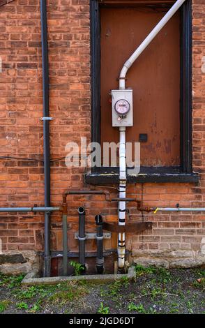 Auspuffrohre und Stromzähler auf alten roten Ziegelwänden Stockfoto