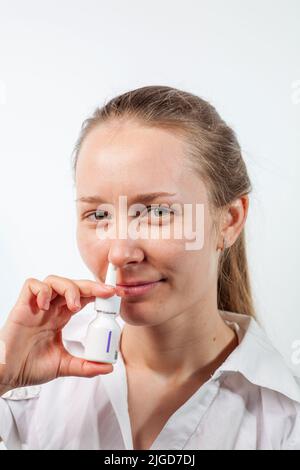 Das Mädchen tropft Nasentropfen aus einer laufenden Nase mit Influenza Stockfoto