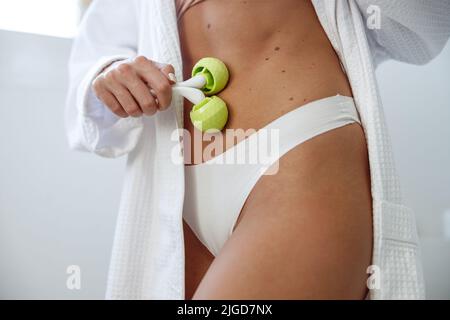 Nahaufnahme einer jungen kaukasischen Frau, die Roller-Massagegerät hält und Bauch anwirbt. Stockfoto