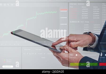 Die besten Trades zu machen. Nahaufnahme eines nicht erkennbaren Geschäftsmannes, der ein digitales Tablet verwendet, während er über einer Infografik der Börse überlagert wird. Stockfoto