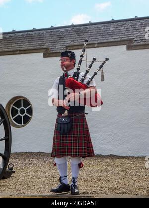 Ein uniformierte Pfeifer spielt Dudelsäcke im Blair Castle in Pitlochry, Perthshire, Schottland, Großbritannien. Stockfoto