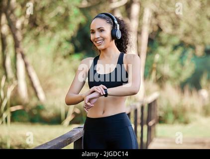 Lassen Sie die Uhr starten und los geht es. Eine sportliche junge Frau, die beim Training im Freien Musik hört. Stockfoto