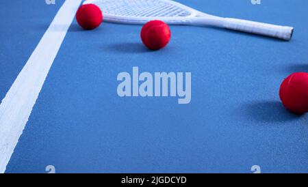 Seine Tenniszeit. Mehrere Tennisbälle liegen auf einem blauen Tennisplatz. Stockfoto