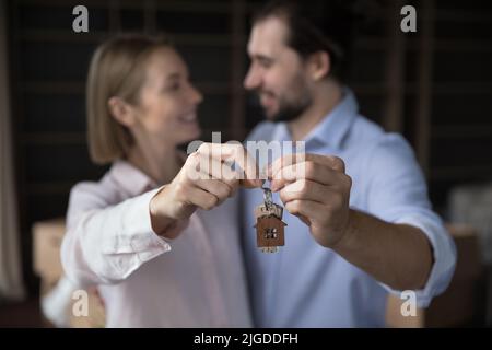 Glückliches Ehepaar von Hausbesitzern, die Schlüssel mit Anhänger zeigten Stockfoto