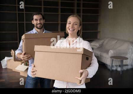 Glückliches fröhliches Ehepaar, das sich gerne bewegt und Kisten trägt Stockfoto