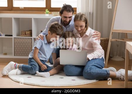 Glückliche Familie, die sich Online-Filme auf einem Laptop ansieht Stockfoto