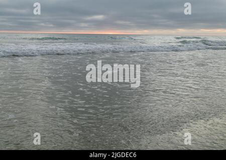 10. Juli 2022, San Diego, CA, USA: Die Korallen, Bäume, Felsen, Strand, Wellen, Orange Wolken und Meer während des glitzernden Sommeruntergangs in La Jolla, Kalifornien, am Samstag, den 9.. Juli 2022 (Bildquelle: © Rishi Deka/ZUMA Press Wire) Stockfoto