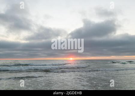 10. Juli 2022, San Diego, CA, USA: Die Korallen, Bäume, Felsen, Strand, Wellen, Orange Wolken und Meer während des glitzernden Sommeruntergangs in La Jolla, Kalifornien, am Samstag, den 9.. Juli 2022 (Bildquelle: © Rishi Deka/ZUMA Press Wire) Stockfoto