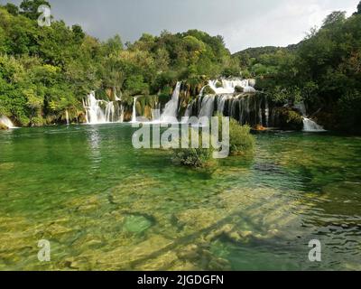 Eine malerische Aussicht auf die wunderschönen Wasserfälle des Flusses Krka, umgeben von dichtem Wald in Kroatien Stockfoto