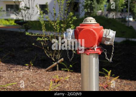 Der lackierte Stahlhydrant steht auf dem Rasen einer mehrstöckigen Wohnung. Hydrant an einem öffentlichen Ort. Stockfoto