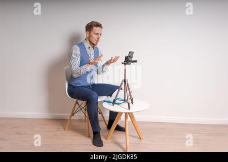 Erstellung von Inhalten für soziale Netzwerke. Bärtiger Mann nimmt selbst ein Video mit einem Telefon auf einem Stativ auf. Moderne Technik und Blog - freiberufliches Arbeitskonzept. Stockfoto