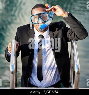 Ein Geschäftsmann, der aus dem Pool kommt, während er Tauchausrüstung trägt. Stockfoto