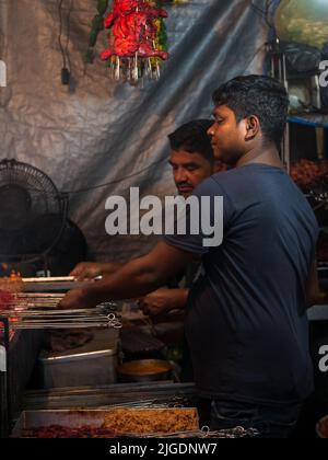 Mumbai, Indien - 1. Mai 2022 : muslimischer männlicher Verkäufer, der im heiligen Monat Ramadan am Straßenrand am Nachtmarkt Halal-Lebensmittel und Kababs verkauft. Stockfoto