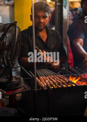 Mumbai, Indien - 1. Mai 2022 : muslimischer männlicher Verkäufer, der im heiligen Monat Ramadan am Straßenrand am Nachtmarkt Halal-Lebensmittel und Kababs verkauft. Stockfoto