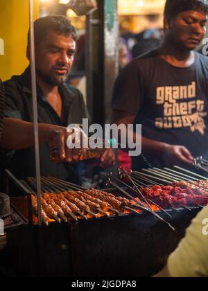 Mumbai, Indien - 1. Mai 2022 : muslimischer männlicher Verkäufer, der im heiligen Monat Ramadan am Straßenrand am Nachtmarkt Halal-Lebensmittel und Kababs verkauft. Stockfoto