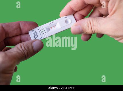 Eigene Hand mit negativem Covid-19-Testergebnis mit SARS CoV-2 Rapid-Antigen-Testkit. Grüner Hintergrund mit Kopierbereich. Infektiöser Schutz des Coronavirus Stockfoto