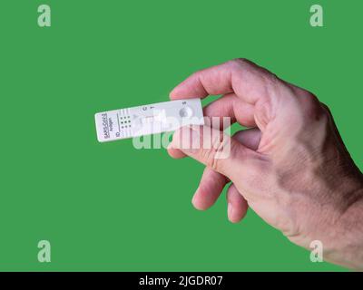 Eigene Hand mit negativem Covid-19-Testergebnis mit SARS CoV-2 Rapid-Antigen-Testkit. Grüner Hintergrund mit Kopierbereich. Infektiöser Schutz des Coronavirus Stockfoto