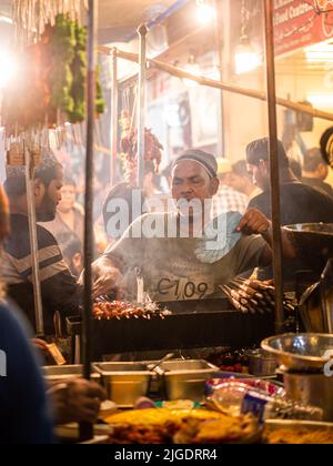 Mumbai, Indien - 1. Mai 2022 : muslimischer männlicher Verkäufer, der im heiligen Monat Ramadan am Straßenrand am Nachtmarkt Halal-Lebensmittel und Kababs verkauft. Stockfoto