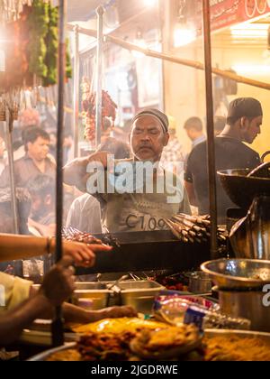 Mumbai, Indien - 1. Mai 2022 : muslimischer männlicher Verkäufer, der im heiligen Monat Ramadan am Straßenrand am Nachtmarkt Halal-Lebensmittel und Kababs verkauft. Stockfoto