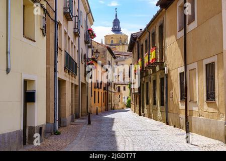 Schmale Gasse mit alten Häusern und Blick auf die Kathedrale von Segovia im Hintergrund, Spanien. Stockfoto