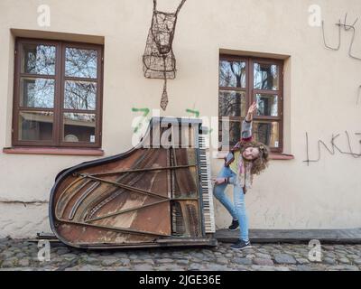 Zarzecze, Vilnius, Litauen - 08. April 2018: Junge Frau und alte Pianistin in Uzupis im Künstlerviertel in Vilnius, Užupis, Osteuropa Stockfoto