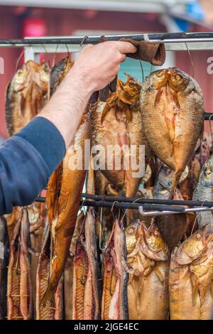 Hängen rauchgetrocknete verschiedene Fische in einem Fischmarkt nur mit Hartholz-Hackschnitzel in einem Raucher geraucht und bereit zu essen, vertikal Stockfoto