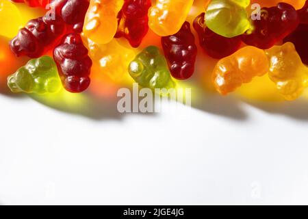 Gummitiere in verschiedenen Farben mit Fruchtsaft liegen auf einem weißen Hintergrund auf dem Rahmen Stockfoto