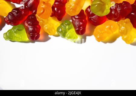 Gummitiere in verschiedenen Farben mit Fruchtsaft liegen auf einem weißen Hintergrund auf dem Rahmen Stockfoto