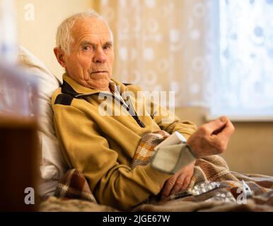 Alter Mann in eine Decke gewickelt, die den Druck mit Tonometer misst Stockfoto