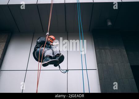 Industriekletterer in Uniform und Helm steigt Stockfoto