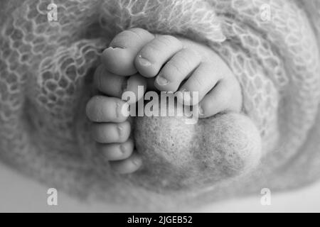 Gestricktes Herz in die Beine eines Babys. Weiche Füße einer neu geborenen Decke. Nahaufnahme von Zehen, Fersen und Füßen eines Neugeborenen. Stockfoto