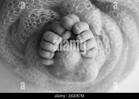 Gestricktes Herz in die Beine eines Babys. Weiche Füße einer neu geborenen Decke. Nahaufnahme von Zehen, Fersen und Füßen eines Neugeborenen. Stockfoto