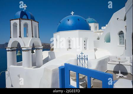 Traditionelle griechisch-orthodoxe Kirchen mit blauer Kuppel in Oia oder Ia auf der Insel Santorini, die zu den Kykladen-Inseln vor dem griechischen Festland gehört Stockfoto