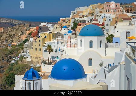 Oia, oder Ia ein malerisches Dorf mit weiß getünchten Häusern und blau gewölbten Kirchen auf der Insel Santorini, Teil der griechischen Kykladen-Inseln. Stockfoto
