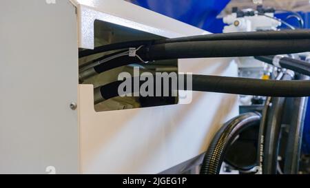 Nahaufnahme großer schwarzer Kabel an der Produktionsmaschine. Elektrische Betriebszahnradausrüstung. Stockfoto