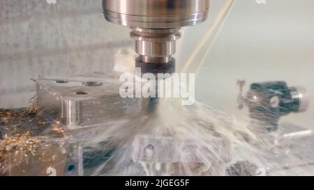 Nahaufnahme-Bohrmaschine mit Wasserspritzern und vielen metallischen Spießen. Nahaufnahme cnc-Bearbeitungszentrum Fräsen mit Kühlmittel. Stockfoto