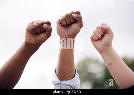 Eine Gruppe von Studenten, die ihre Fäuste erheben, um draußen zu protestieren. Stockfoto