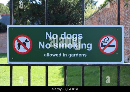 Ein Schild am Metalltor in das Gelände des öffentlichen Gartens, auf dem darauf hingewiesen wird, dass Hunde und Rauchen nicht gestattet sind Stockfoto